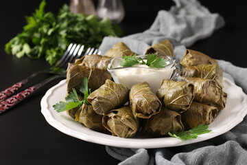 Dolma - stuffed grape leaves with rice and meat on black background. Traditional Caucasian, Greek, Ottoman and Turkish cuisine, Closeup