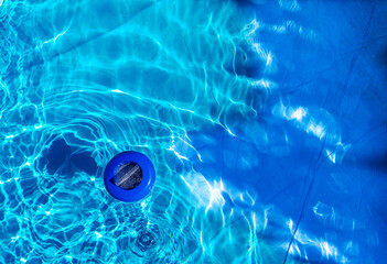 Floating plastic chlorine dispenser and blue water seen from above