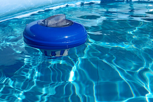 Blue chlorine dispenser floating on a swimming pool