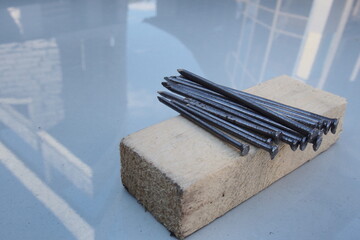 Steel construction nails of different lengths for working with wood building materials, a bundle lie on a wooden bar without packaging