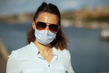 trendy woman with medical mask and sunglasses outdoors in city