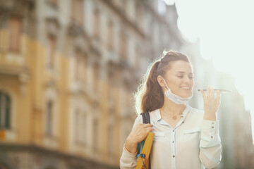 smiling modern woman using call center outdoors in city