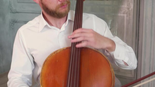 A man plays a bow on cello in the Studio. Panorama from a man to his hands
