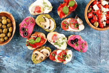 Assorted bruschetta with various toppings. Appetizing bruschetta or crudo crostini. Variety of small sandwiches. Mix bruschetta with tomatoes and basil