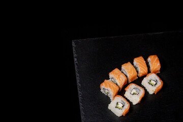 Philadelphia roll with salmon, cheese and cucumber on a black background. Sushi Philadelphia