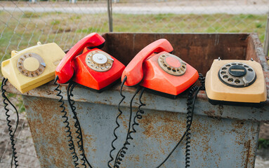 Many multicolored old-fashioned phones stand on a metal urn, with the handsets off, in preparation...