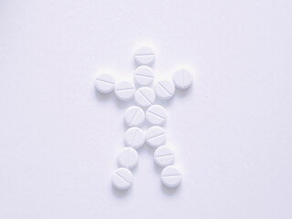 Pills on a white background stacked in the form of an abstract silhouette of a man. Table view.