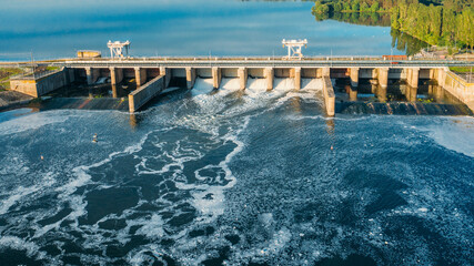 Dam with flowing water through gates. Hydroelectric power station, aerial top view.