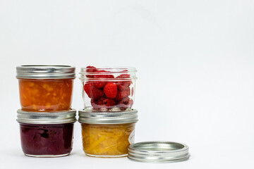 Three Home Made Preserves Jam Jars and a Canning Jar of Fresh Raspberries