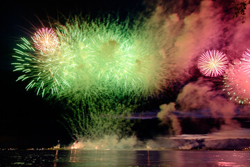 Colorful fireworks reflect from water, beautiful scenery