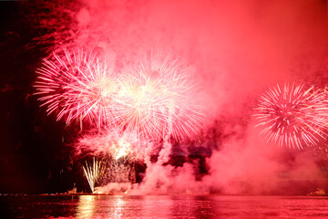 Holiday fireworks above water with reflection on the black sky background