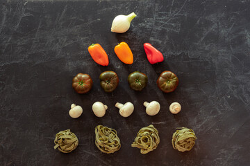 Green spaghetti and vegetables on a black background. Vegan food. Italian Cuisine. Top view, flat lay