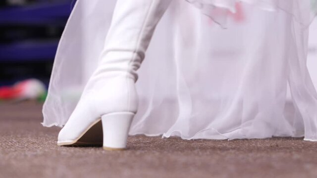 woman in white high boots and dress dances at hockey match