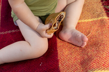 a child on a picnic. a croissant in a child's hand