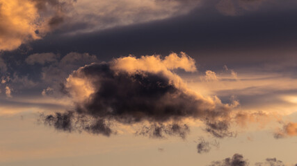 Small storm cloud glowing orange at sunset background and copy space. Beautiful clouds and puffy...