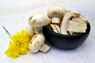 mushrooms in clay bowl on table with lacy towel