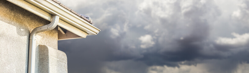 House with New Seamless Aluminum Rain Gutters With Storm Background Banner © Andy Dean