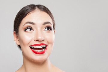 Young woman with braces on teeth on white, beautiful female face close up