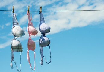 Three pretty bras hanging on the clothesline in the summer.
