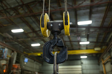 selective focus close up view of lifting hook with safety latch attached to sheaves suspended by...