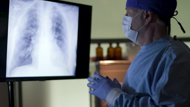 A surgeon reviews the results of an x-ray of a COVID19 patient on a computer screen before starting treatment.