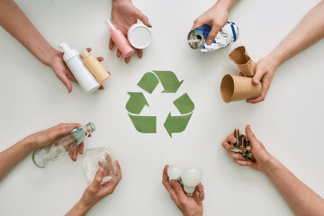 Go green with recycling. Top view of many hands holding different waste, garbage types with...