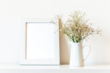Blank picture frame and Gypsophila flowers in white jug, mock up.