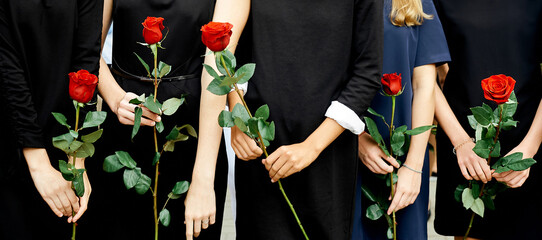 five girls in dark dresses hold one rose flower