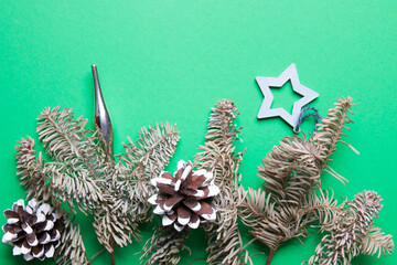 branches of decorative fir decorated with pine cones and Christmas toys, green background copy space