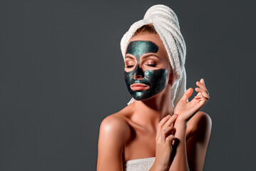 Beautiful woman with green peel-off mask on a gray background.