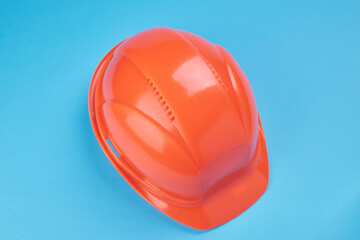 orange protective helmet and safety glasses near it on a bright blue background. protective workwear and construction industry concept.