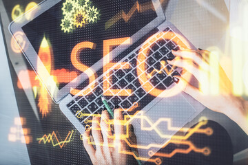 Double exposure of woman hands working on computer and SEO hologram drawing. Top View. Search optimization concept.