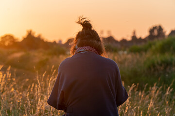 Beautiful asian woman standing on grass field with landscape of sunset in summer