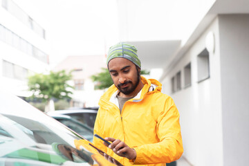 young man  with smart phone and yellow jacket using car sharing