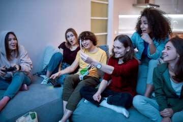 Happy young man showing marijuana joint or hashish cigarette while relaxing with friends on the...