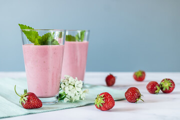 Milk strawberry cocktail in tall glasses, decorated with fresh mint, flowers and strawberries