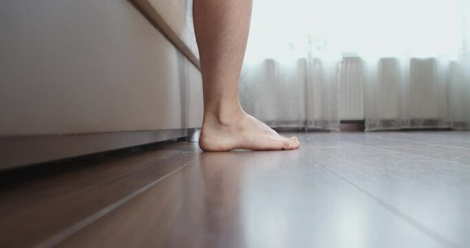 A man wakes up and gets out of bed. Close-up of male foot, man waking up from bed in the morning.