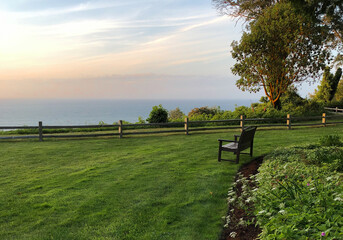 Empty bench on manicured green lawn overlooking Puget Sound during pastel sunset