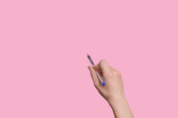 The girl holds a pen in her hand and writes something in the air.