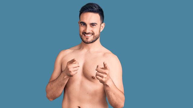 Young handsome man wearing swimwear pointing fingers to camera with happy and funny face. good energy and vibes.
