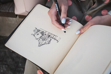 Sketchbook with a drawing of a house close-up. Girl draws in the fresh air. - obrazy, fototapety, plakaty
