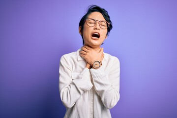 Young beautiful asian girl wearing casual shirt and glasses standing over purple background shouting suffocate because painful strangle. Health problem. Asphyxiate and suicide concept.