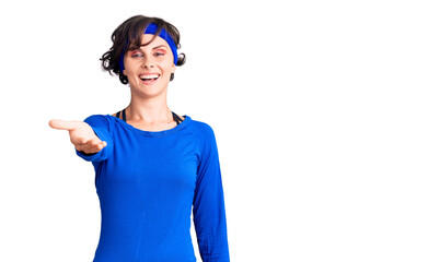 Beautiful young woman with short hair wearing training workout clothes smiling friendly offering handshake as greeting and welcoming. successful business.