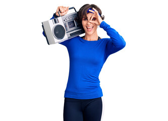 Beautiful young woman with short hair wearing workout clothes and holding boombox smiling happy doing ok sign with hand on eye looking through fingers