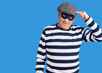 Senior handsome man wearing burglar mask and t-shirt smiling pointing to head with one finger, great idea or thought, good memory