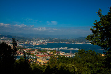 Aerial view of the northern Italian city of La Spezia, taken from a hilltop overlooking the city. Image shows port region with dockyard by the mediterranean sea as well as other coastal buildings. 