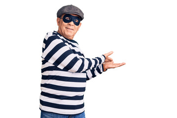 Senior handsome man wearing burglar mask and t-shirt inviting to enter smiling natural with open hand