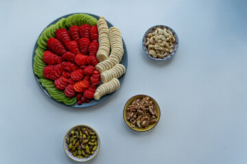 Fruit plate including strawberry, banana and kiwi and three small nut plates including pistachio, walnut, cashew