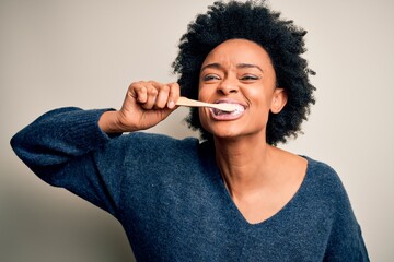 African american woman brushing her teeth using tooth brush and oral paste, cleaning teeth and...