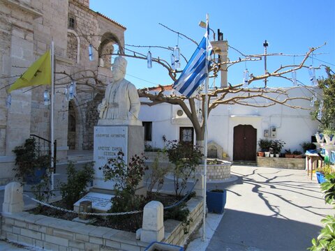 View outside the Church of the Transfiguration of Christ the Savior in the Castle of Lycourgos Logothetes with a statue and water bottles in a tree in Pythagorio on the Greek island of Samos